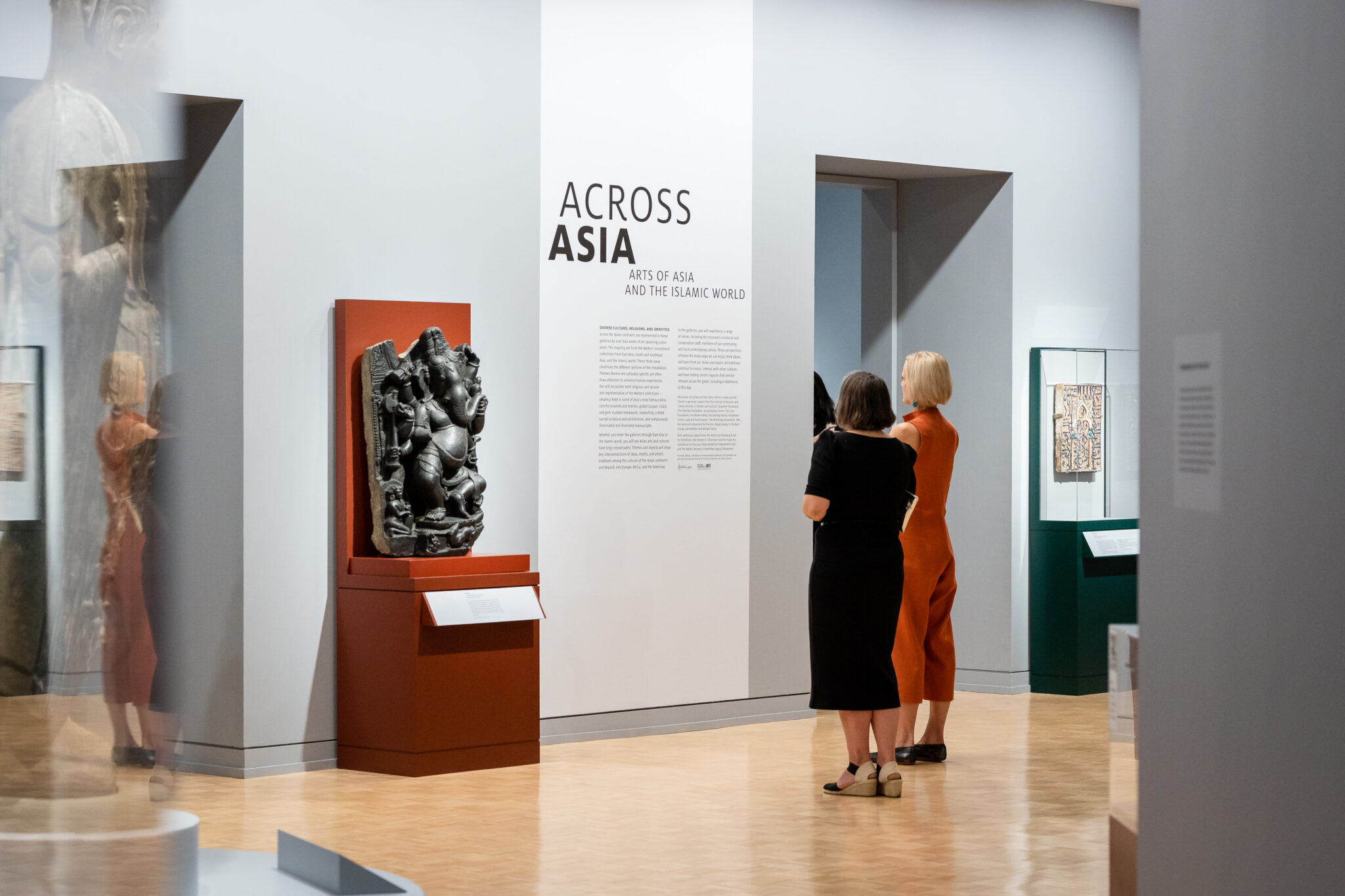 Two visitors in front of the title wall for Across Asia
