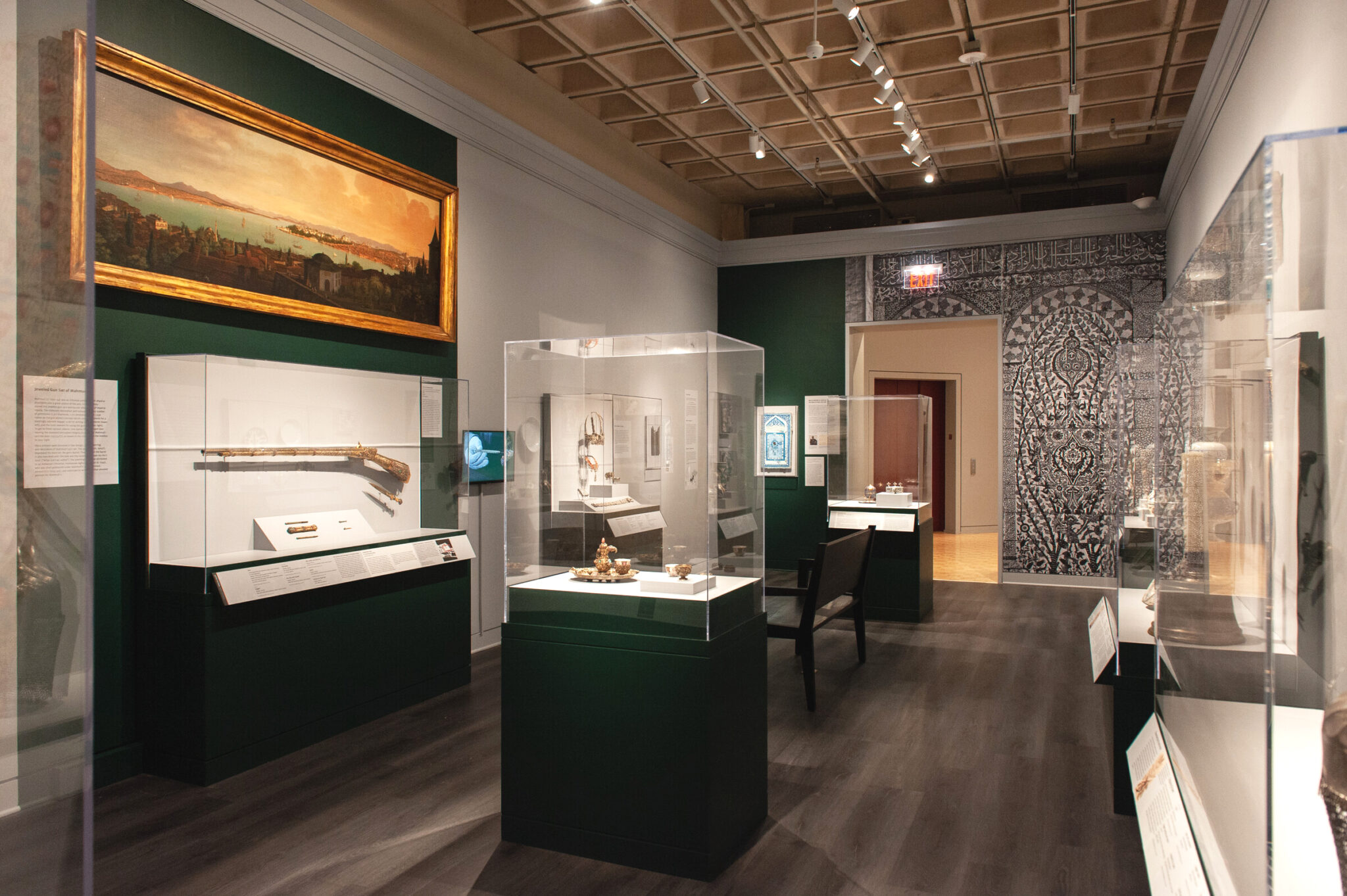 View of gallery with large wall graphic on far wall and cases with art objects