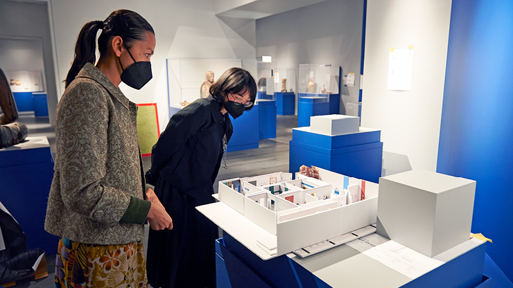 museum professionals examine a model of the museum galleries