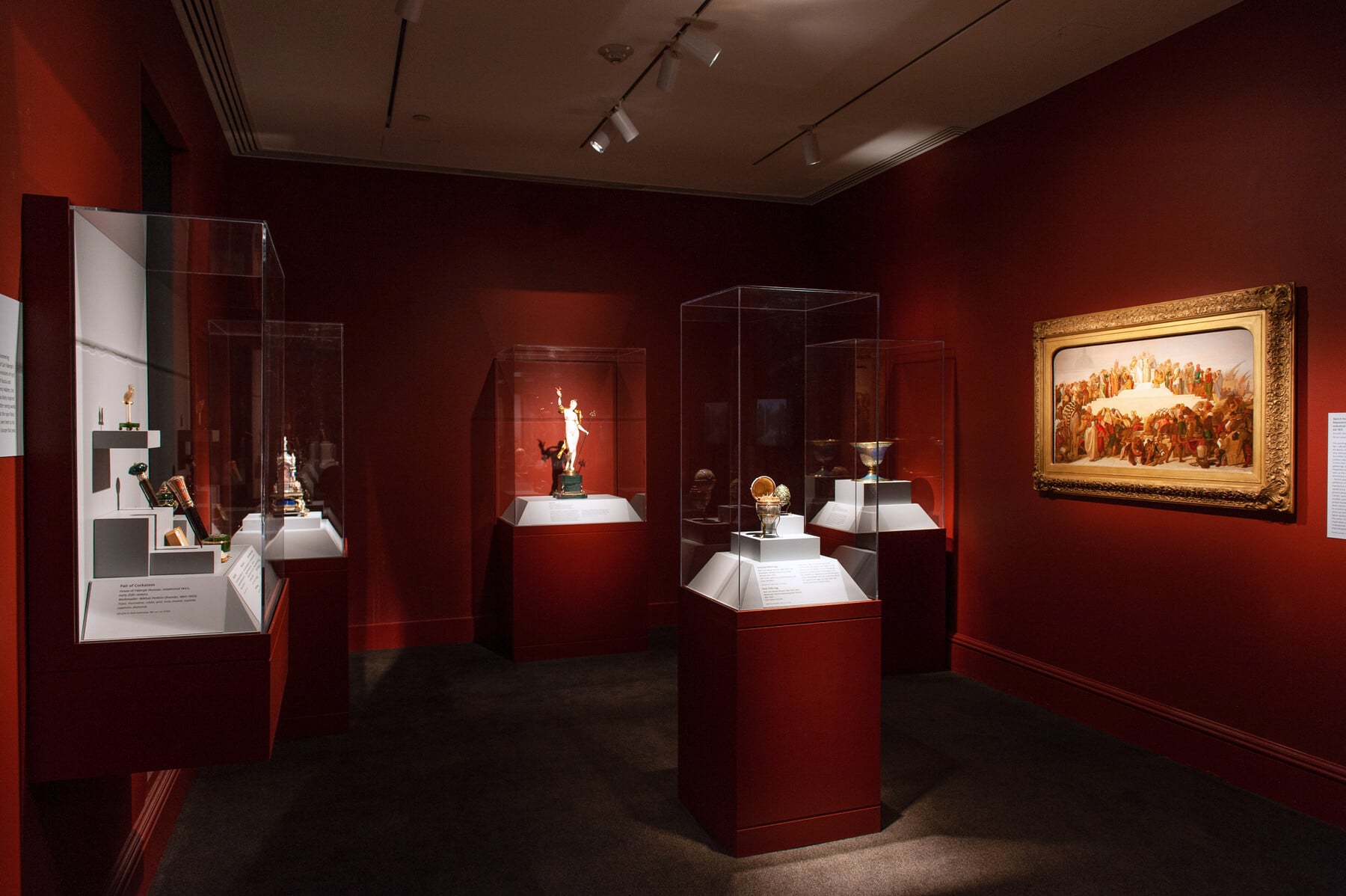 An in-gallery view of Distinctive Design with several cases of art objects and a painting on the wall