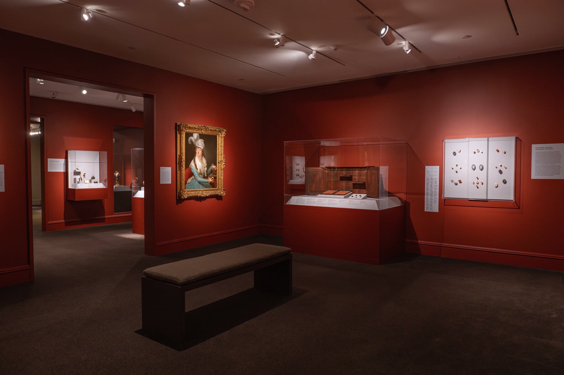 An in-gallery view of Distinctive Design with several cases of art objects and a painting on the wall