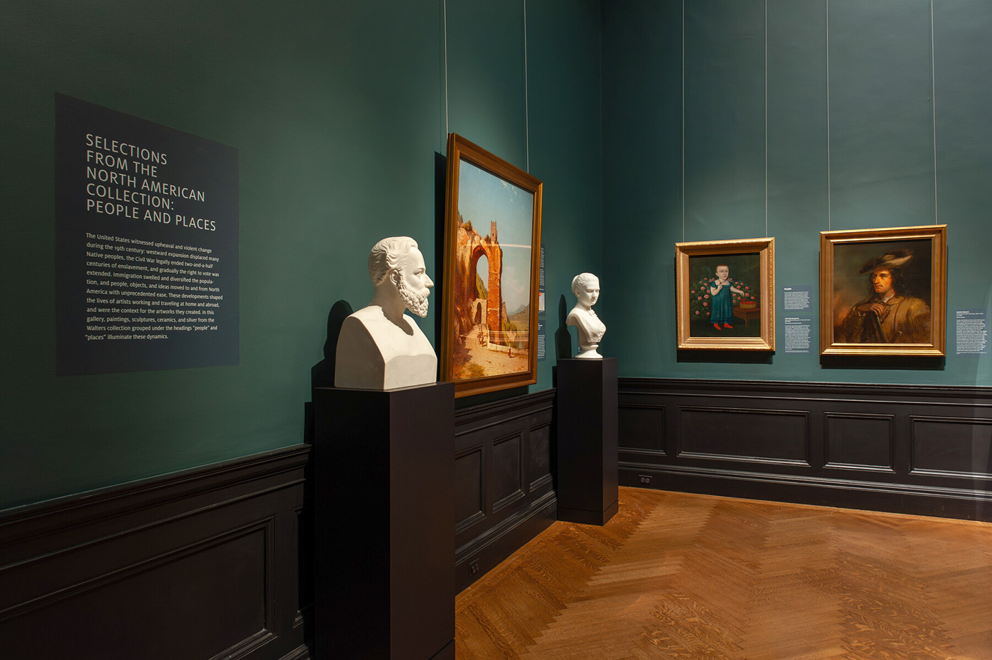 In-gallery view of Selections from the North American Collection: People and Places, which shows the introduction text, sculptures, and paintings.