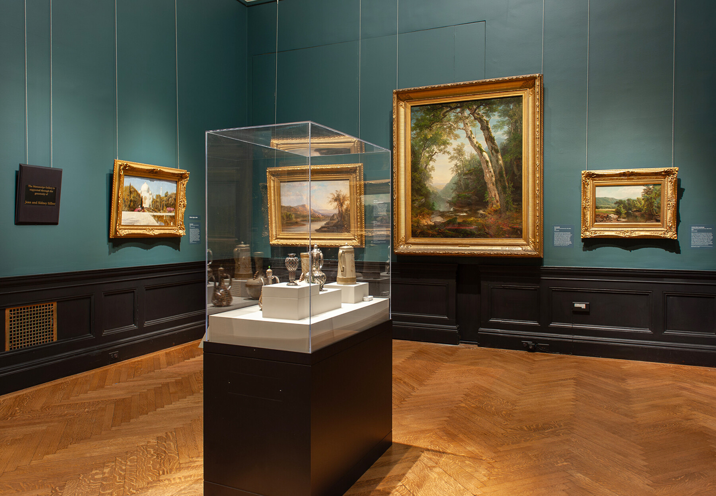In-gallery view of Selections from the North American Collection: People and Places, which shows art objects in a case and paintings.