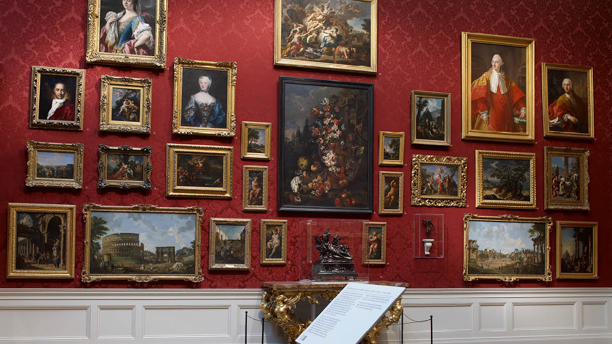 The red gallery, a salon-style installation of paintings against a red wall
