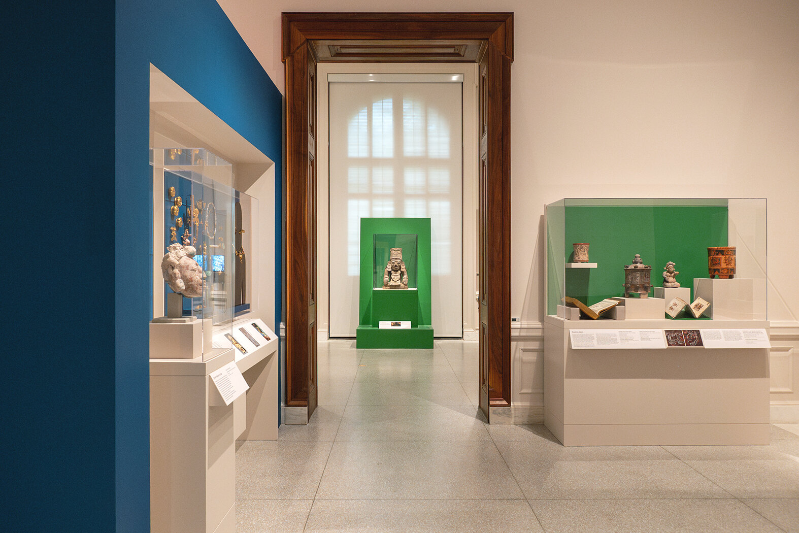 Looking from one gallery into the next with several cases of art objects