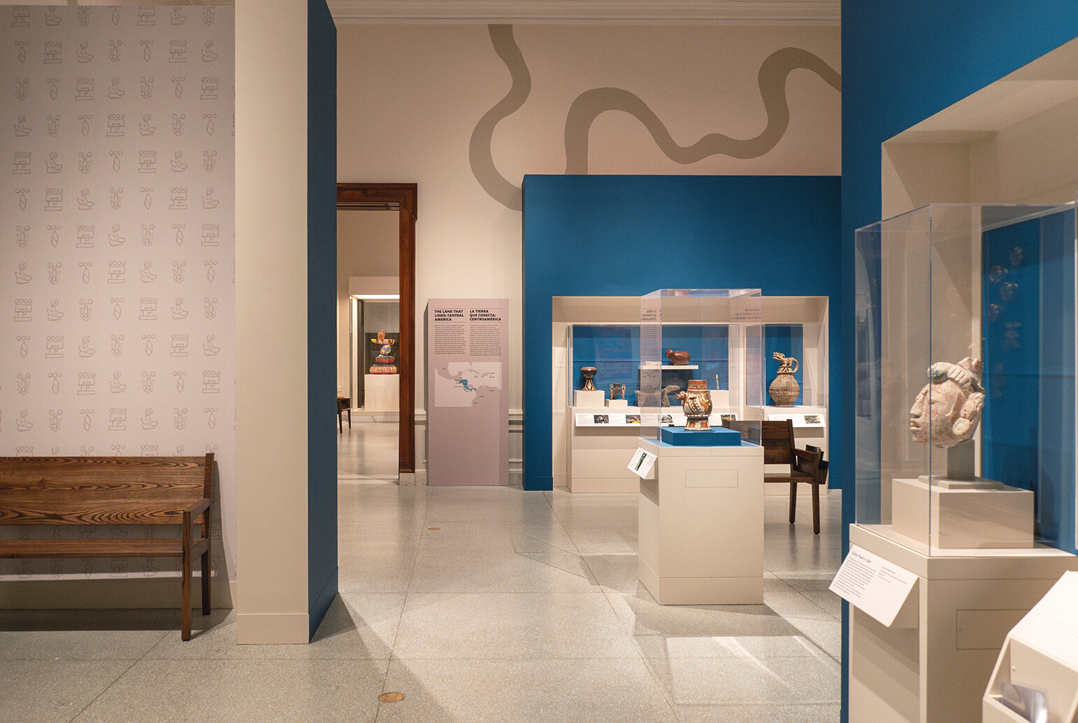 Another view of a text panel, several cases, and the river design on the wall