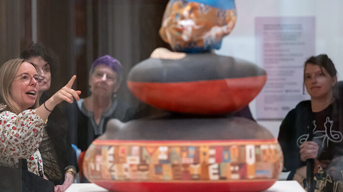 Visitors and a tour guide observe a sculpture
