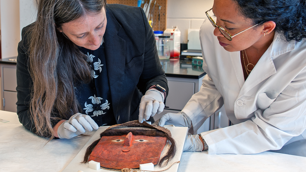 Conservators examine an object from the collection of ancient american art.