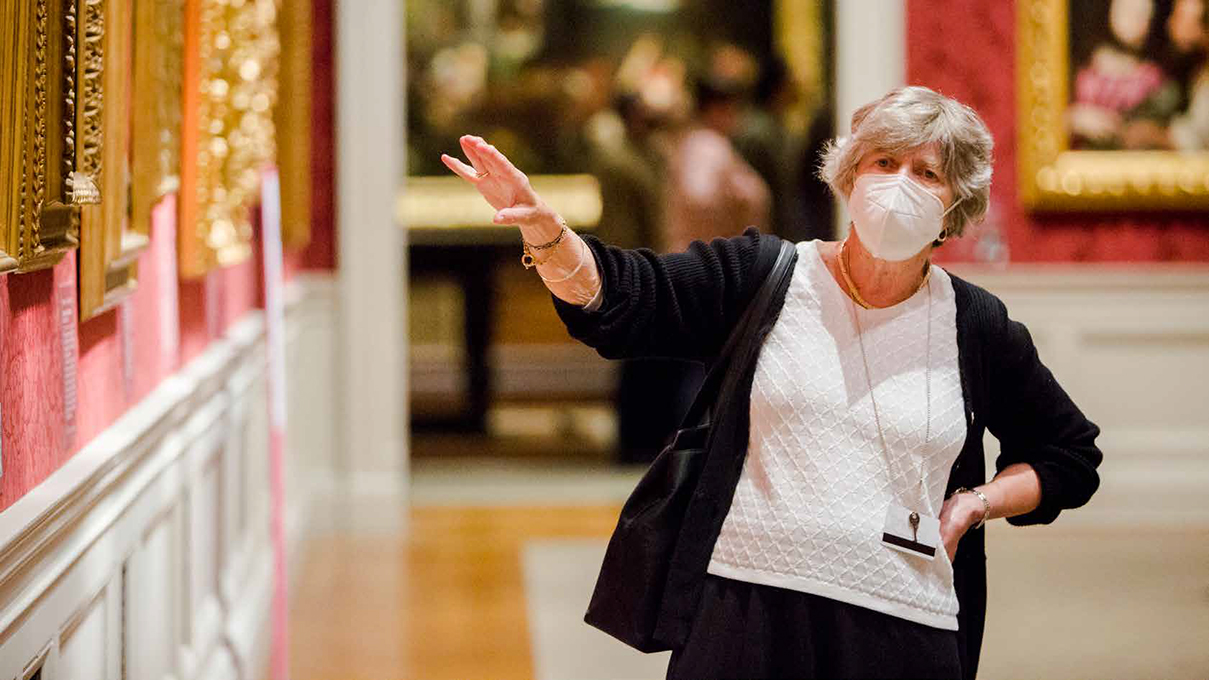 A museum docent points to an artwork