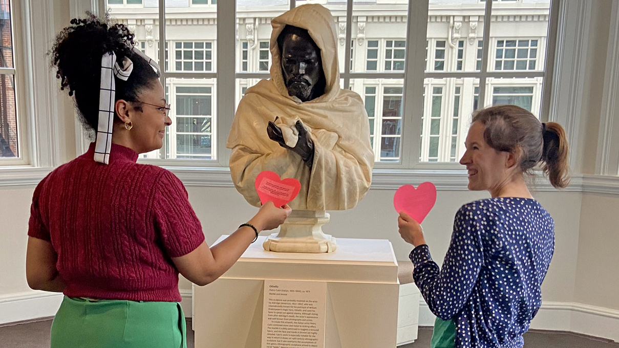 museum visitors placing red paper hearts near artworks that they love.