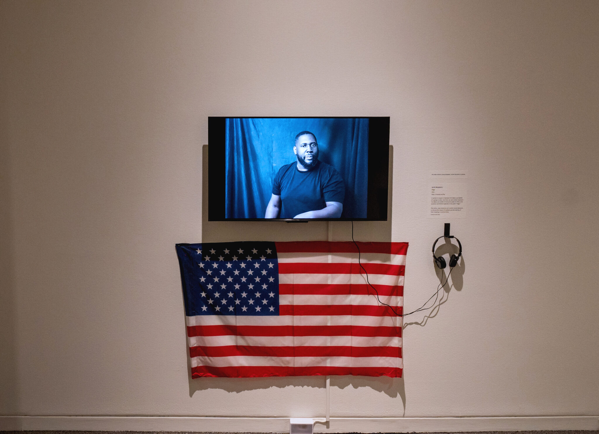 Gallery wall with a video by Jacob Mayberry and an American flag beneath