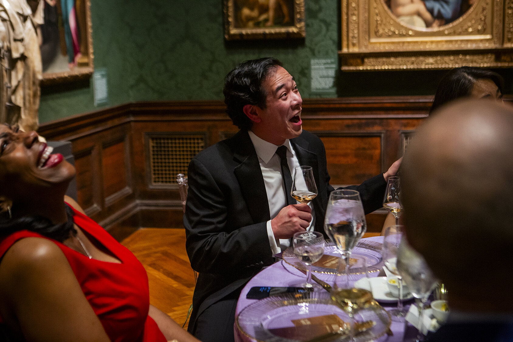 A gala guest sits at a table in a gallery
