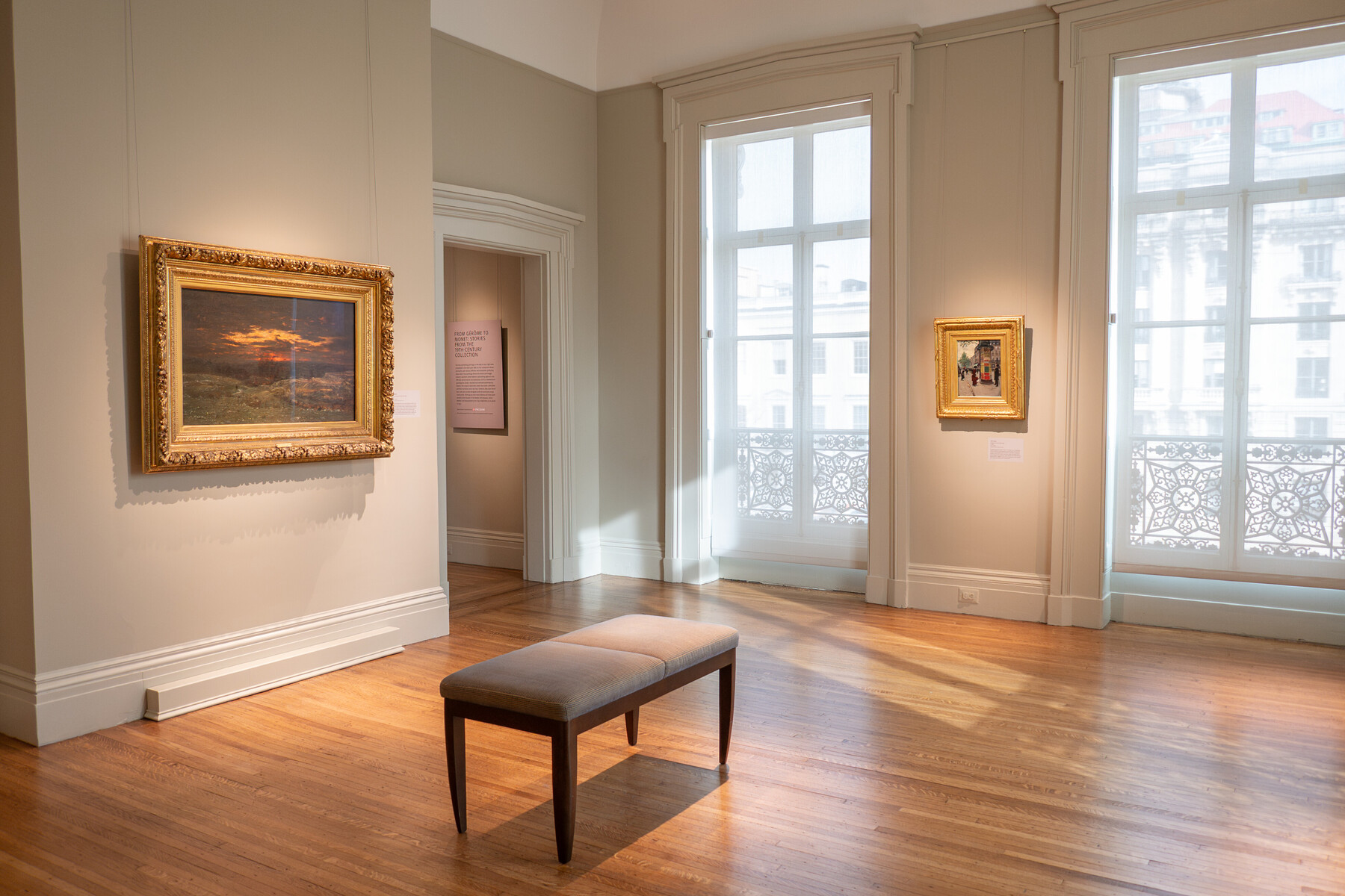 Two paintings in a gallery with a text panel in the room in the background