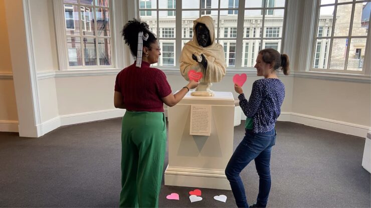 a museum visitor places a red heart-shaped valentine card near a beloved artwork