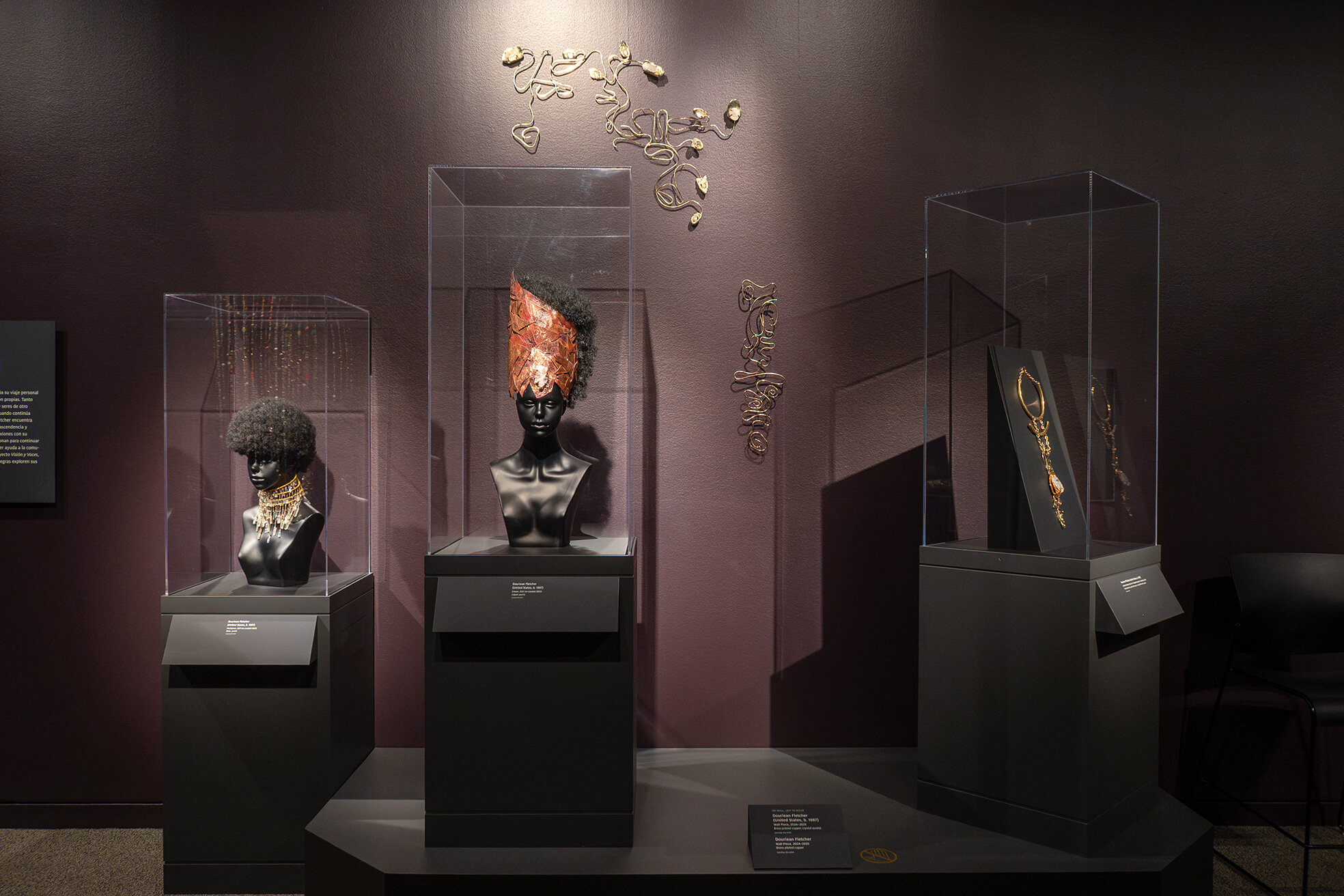 Cases displaying jewelry and adornments with metal sculptures on wall in the exhibition Douriean Fletcher: Jewelry of the Afrofuture