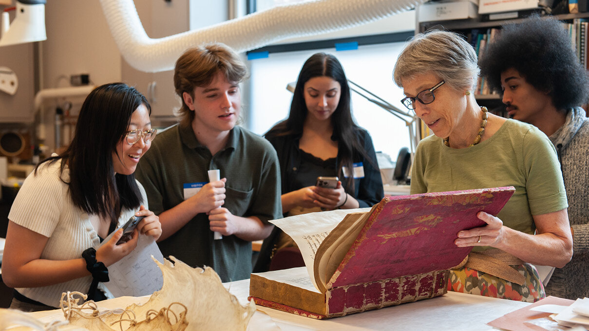 College students meet with a museum professional to see a manuscript in conservation
