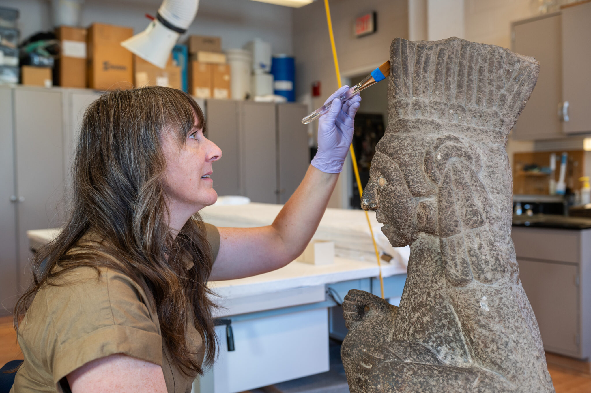 A conservator works on a stone art object