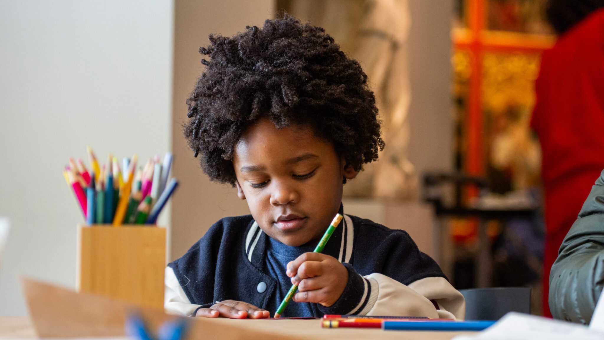 A child draws with colored pencils