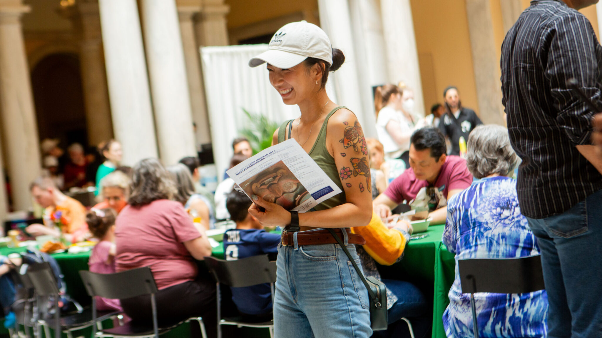 A visitor stands smiling in the foreground with many other museum-goers behind