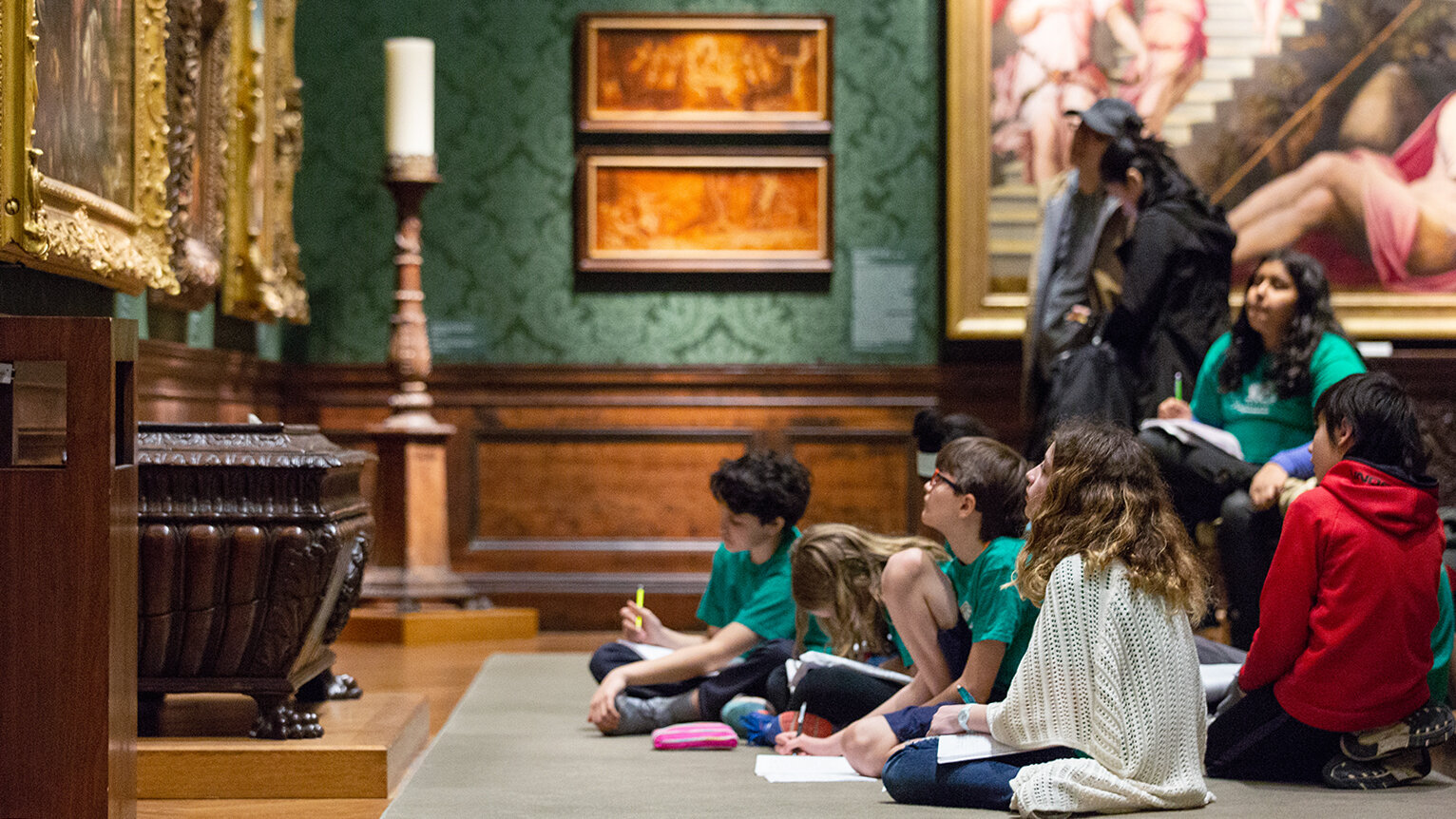 A group of students work on worksheets in a gallery