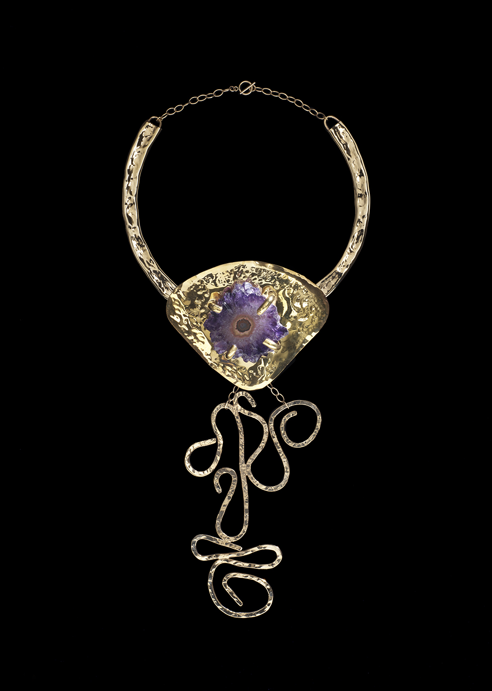 A golden necklace with a stone set in the center made by Douriean Fletcher