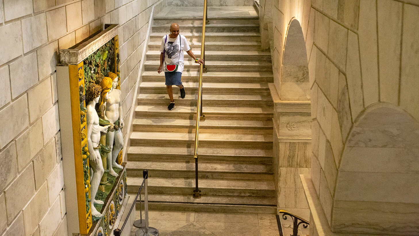A visitor descends the staircase toward the Sculpture Court