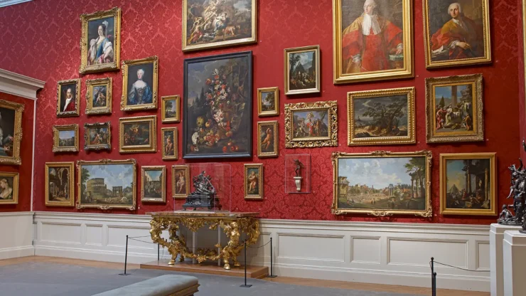 a red-walled gallery filled with beautiful paintings
